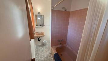 A bathroom with a bathtub, a shower, a sink, and a mirror.