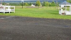A paved area with a white fence and a small white structure, possibly a gazebo, under a cloudy sky. - Countryview Motel and Restaurant  (Steeves Mountain)
