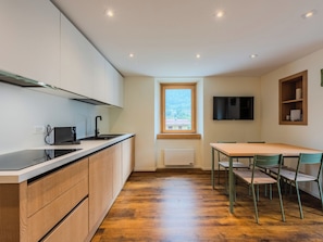 A compact kitchen with modern appliances, a dining area with a table and chairs, and a window with a view of the outdoors. - Ca' Alma Dolomia by Interhome (Strembo)