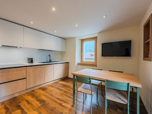A modern kitchen with wooden cabinets, a black countertop, and a window overlooking a mountainous landscape. - Ca' Alma Dolomia by Interhome (Strembo)