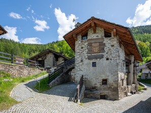 A stone building with a wooden roof, a staircase leading up, and a cobblestone path.