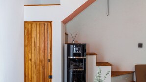 Ein Essbereich mit einem Holztisch, gedeckt für vier Personen, einer Vase mit Blumen und einem schwarzen Gerät im Hintergrund.
