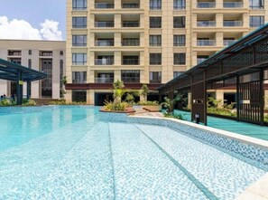 Ein Hotel mit Schwimmbad, überdachtem Außenbereich und einem mehrstöckigen Gebäude mit Balkonen.