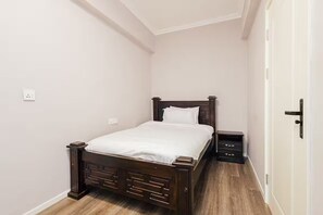 A bedroom with a wooden bed, a nightstand, and a dresser. - Upscale 3-Bedroom Apartment in Prime Kilimani (Nairobi)