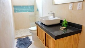 A bathroom with a white sink, a wooden vanity, a green soap dispenser, and a blue rug on the floor. - Boho 1-Bedroom Apartment with Fast Wi-Fi in Downtown, Perfect for Working Near the Hotel District (Cancún)