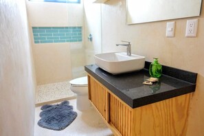 A bathroom with a white sink, a wooden vanity, a green soap dispenser, and a blue rug on the floor. - Boho 1-Bedroom Apartment with Fast Wi-Fi in Downtown, Perfect for Working Near the Hotel District (Cancún)