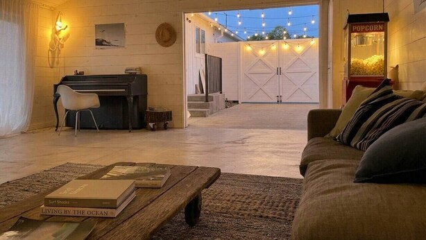 Ein gemütliches Wohnzimmer mit Klavier, Popcornmaschine und Blick auf eine Garage.