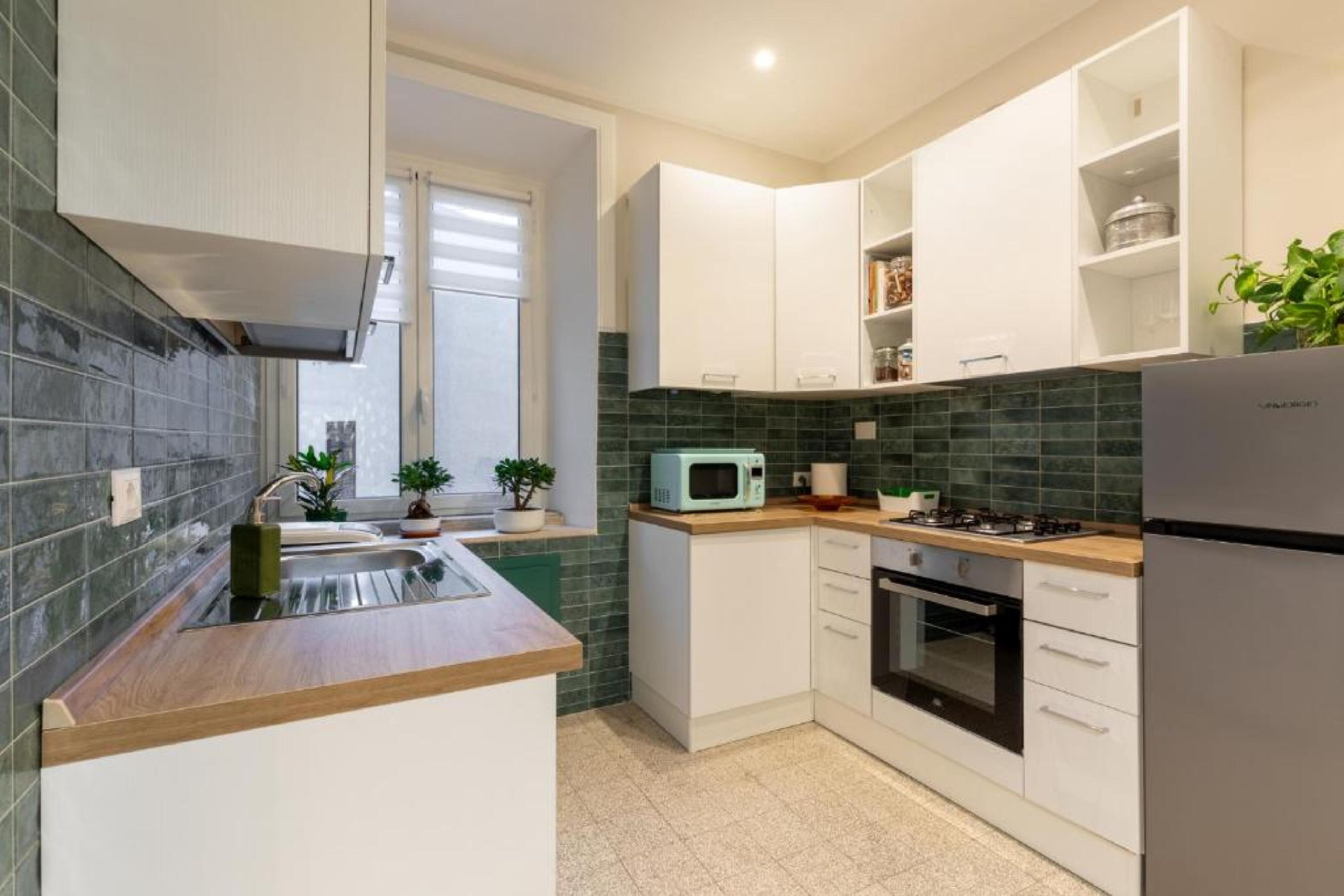A modern kitchen with white cabinets, a microwave, a stove, and a refrigerator.