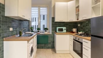Una cocina compacta con lavadora, microondas y estufa.