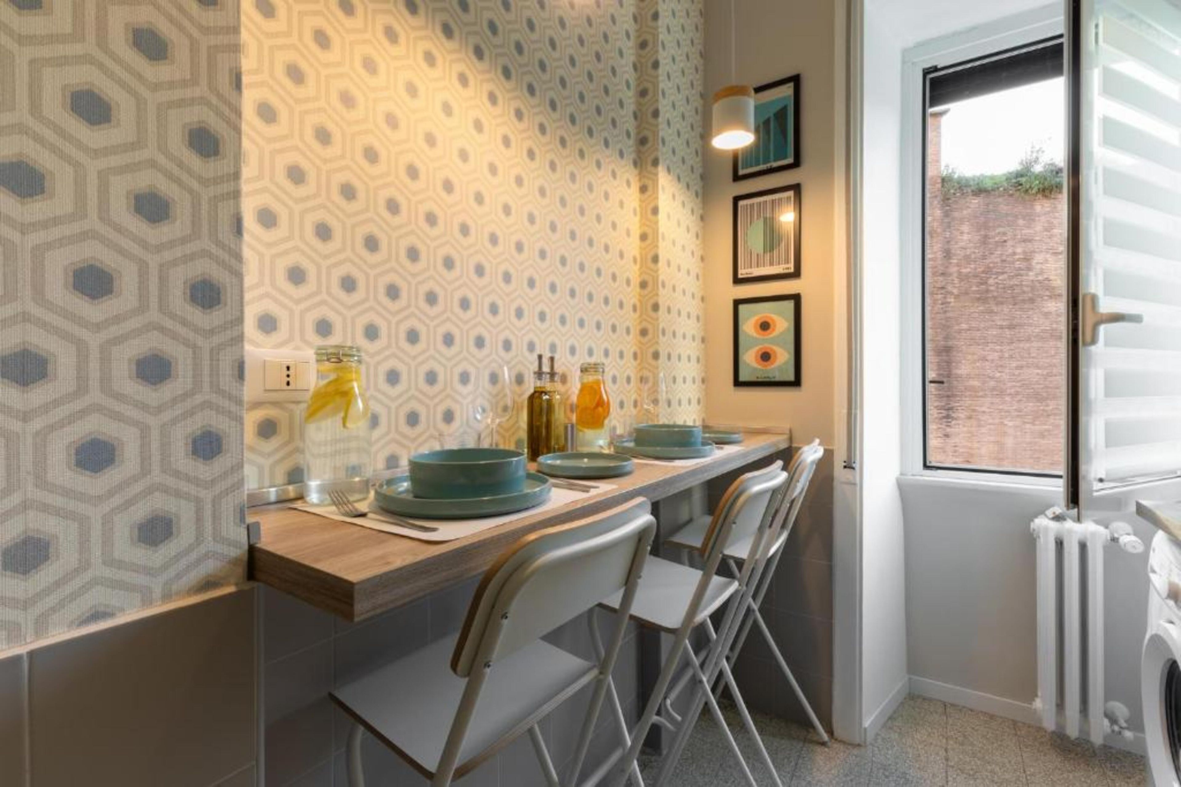 Une cuisine avec un mur de crédence à motifs, une fenêtre donnant sur un beau paysage et un radiateur.