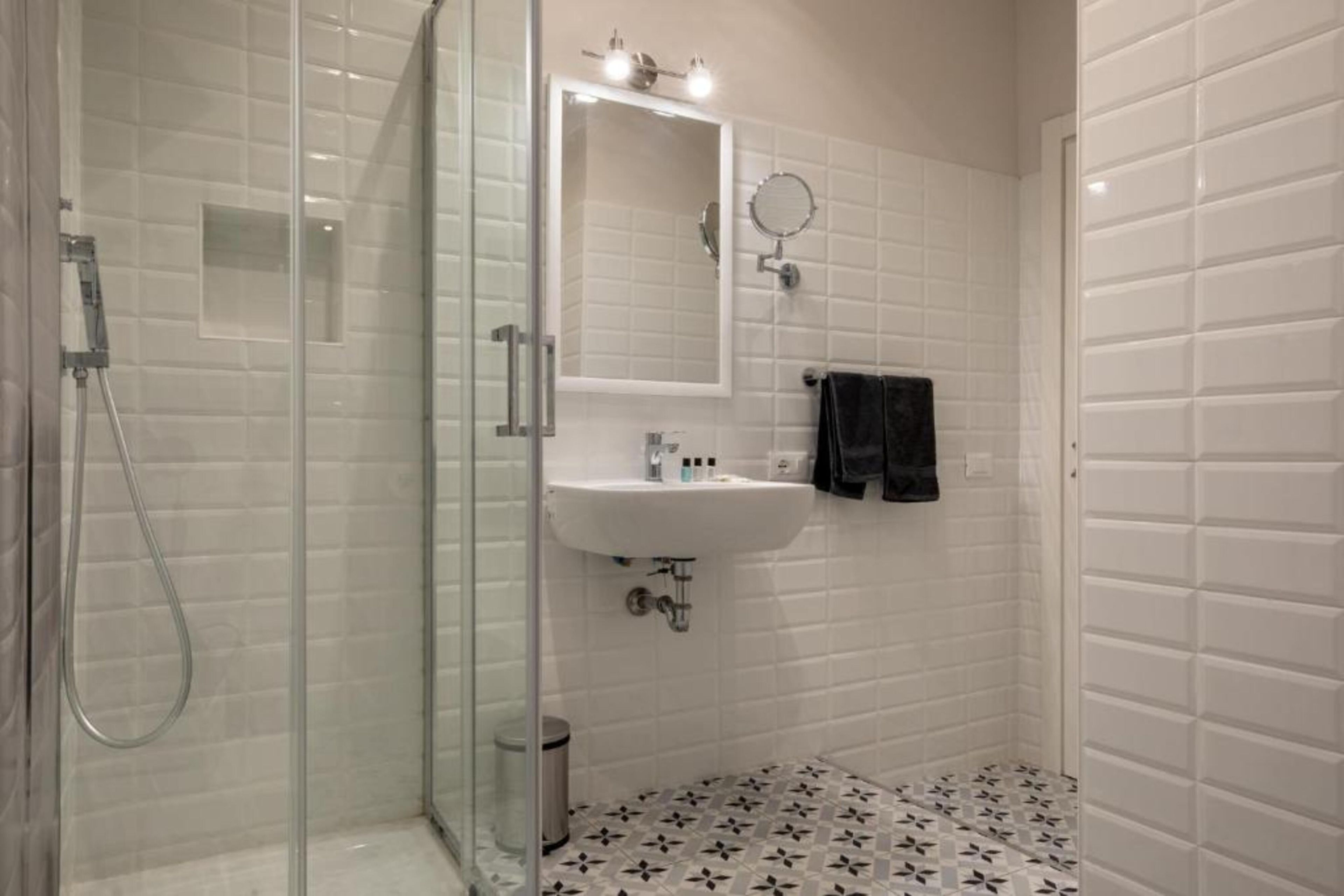 Un baño con cabina de ducha de vidrio, un lavabo blanco y un espejo.
