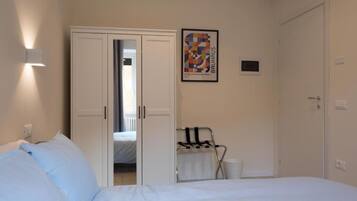 A hotel room with a bed, a wardrobe, a radiator, and a poster on the wall.