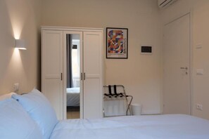 A hotel room with a bed, a wardrobe, a radiator, and a poster on the wall. - Brick & Arch (Roma)