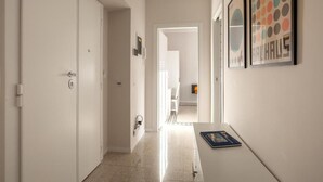 A hallway with white walls, a door on the left, and a framed picture on the right. - Brick & Arch (Roma)