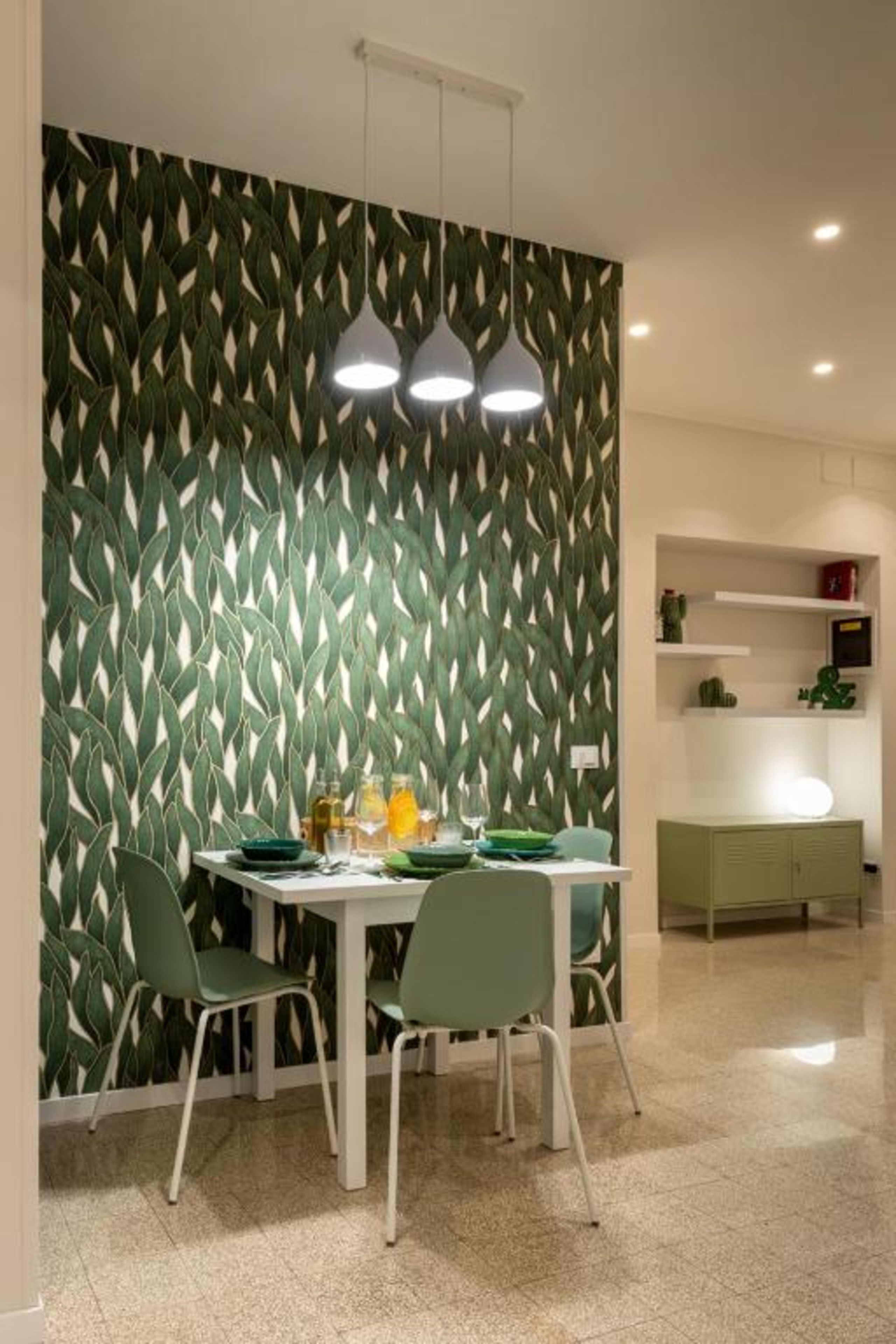 A dining area with a table, chairs, and a wall with a leaf pattern.
