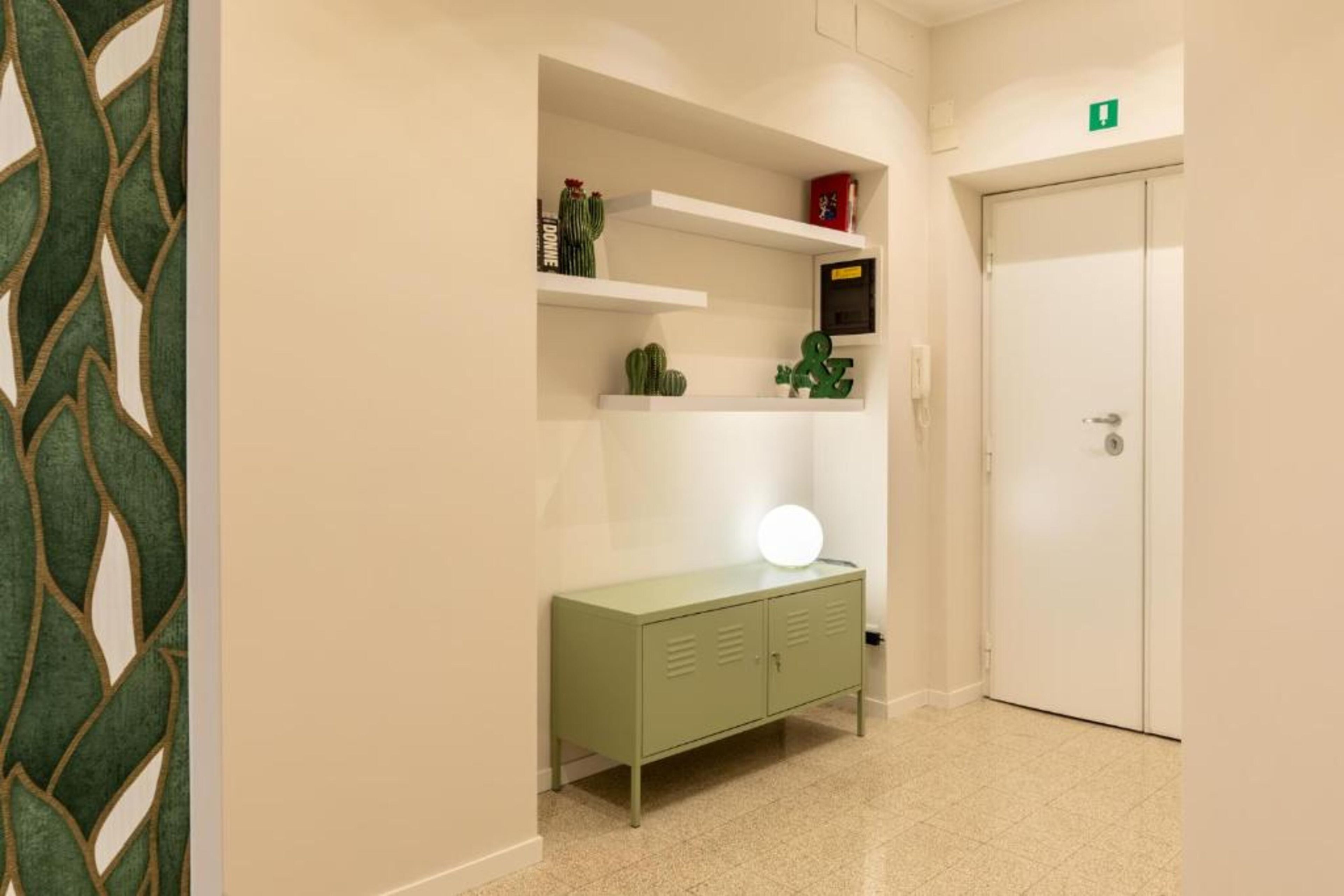 Ein Flur mit einem grünen Schrank, einer weißen Tür und einem Regal mit Dekorationen.