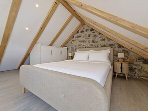 A bedroom with a sloped ceiling, a bed, a wardrobe, and a nightstand with a lamp. - Vacation home Ana by Interhome (Trilj)