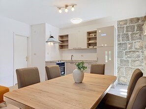 A modern kitchen with a dining area, stone wall, and a vase with plants. - Vacation home Marija by Interhome (Trilj)