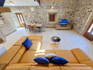 A cozy living room with a sofa, a dining table, and a stone wall. - Vacation home Marija by Interhome (Trilj)