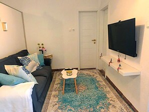 A living room with a sofa, a small table, a flat-screen TV, and a patterned rug. - Valerija by Interhome (Labin)