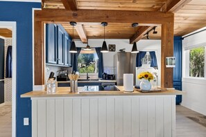 A kitchen with wooden beams, a central island, and a view of the outdoors. - Clear Lake Getaway Boat Parking + Lake Access (Clearlake Oaks)