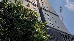 Ein hohes Gebäude mit modernem Design, das ein markantes vertikales Element und eine Reihe von Fenstern aufweist.