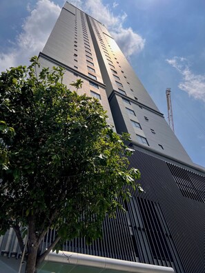 A tall building with a modern design, featuring a prominent vertical element and a series of windows. - Soho residence studio apartment (Ho Chi Minh City)