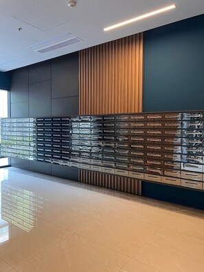 A modern interior with a reflective storage unit, recessed lighting, and a combination of dark and light wall panels. - Soho residence studio apartment (Ho Chi Minh City)