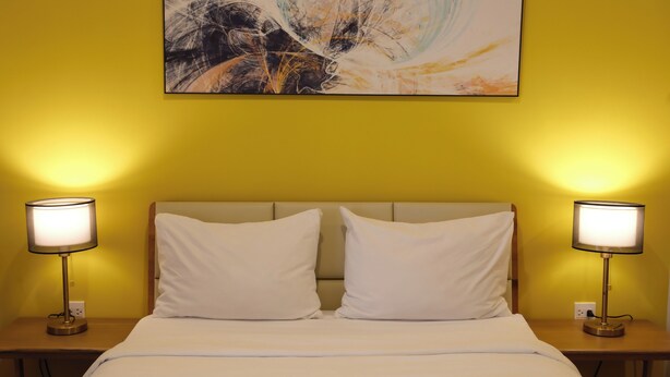 Ein Hotelzimmer mit einem Bett, zwei Nachttischlampen und einem Bild an der Wand.