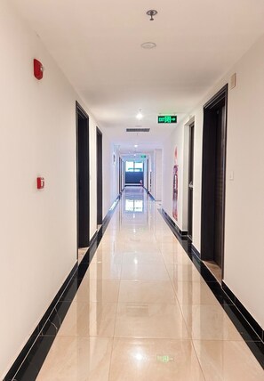 A long, well-lit hallway with a shiny floor, doors on both sides, and an exit sign at the end. - Soho residence studio apartment (Ho Chi Minh City)