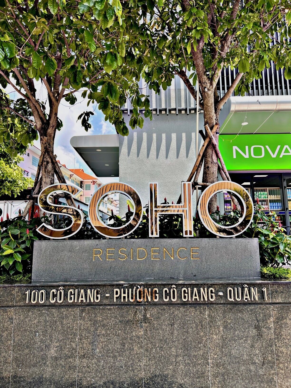 En skylt för ”SOHO Residence” med en modern design, där namnet är skrivet med stora bokstäver och en rund spegel utgör ett dekorativt element.