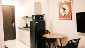 Eine kleine Küche mit Kühlschrank, Mikrowelle und Wasserkocher. Ein kleiner Esstisch mit zwei Stühlen steht bereit.