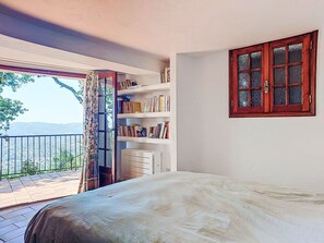 Une chambre à coucher avec un lit, une bibliothèque, une fenêtre avec des rideaux et une vue sur la ville.