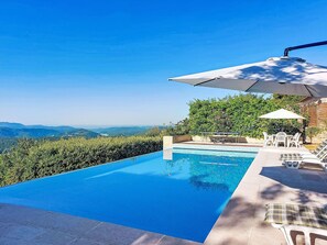 A swimming pool with a clear view of distant mountains, surrounded by a patio area with outdoor furniture. - Balcon d´Azur by Interhome (Spéracèdes)