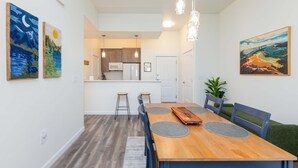 Un comedor con una mesa de madera, sillas y una cocina al fondo.