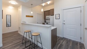 Cocina moderna con isla blanca, taburetes de madera y luces colgantes.