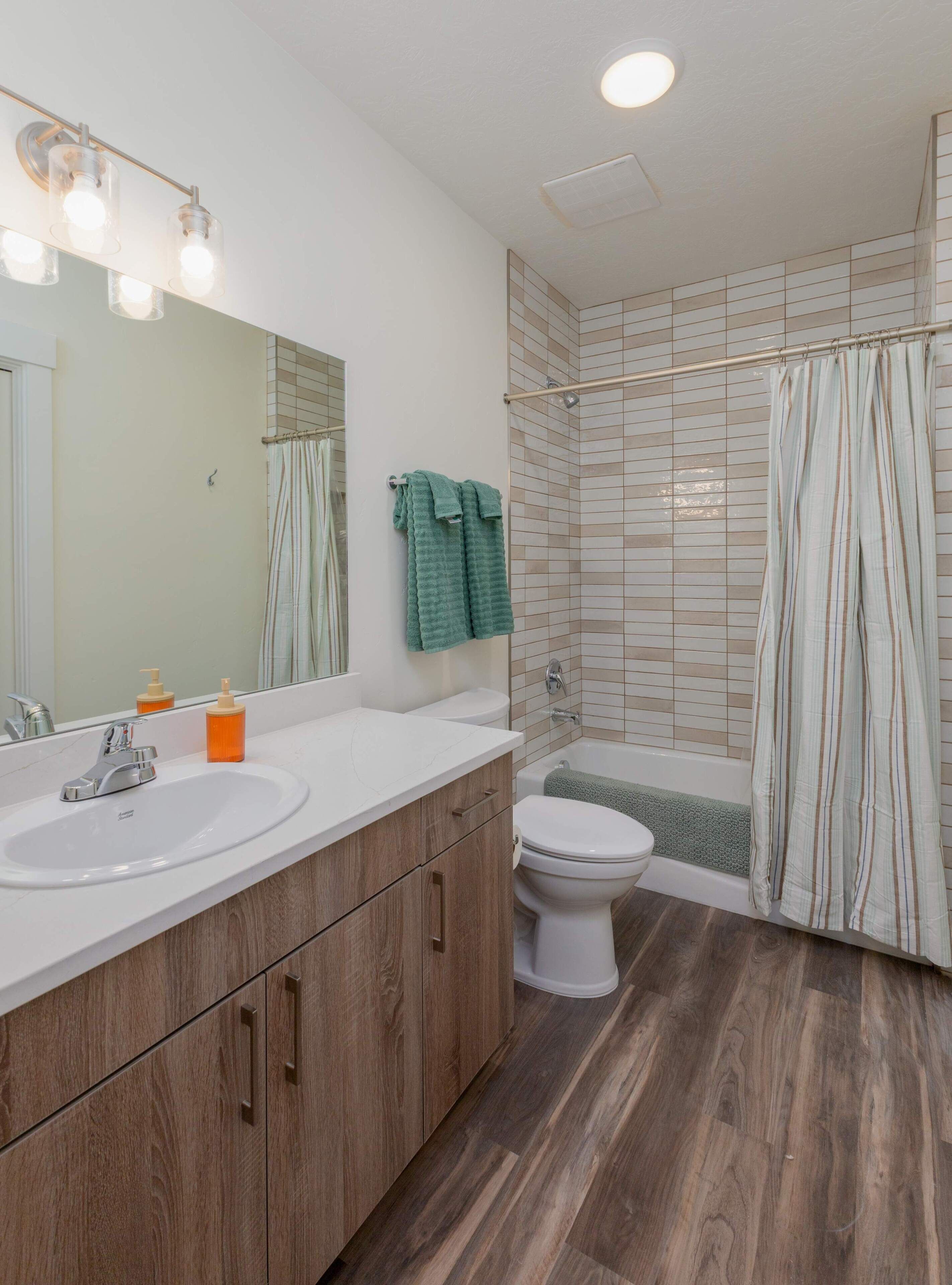 A bathroom with a sink, mirror, toilet, and shower.
