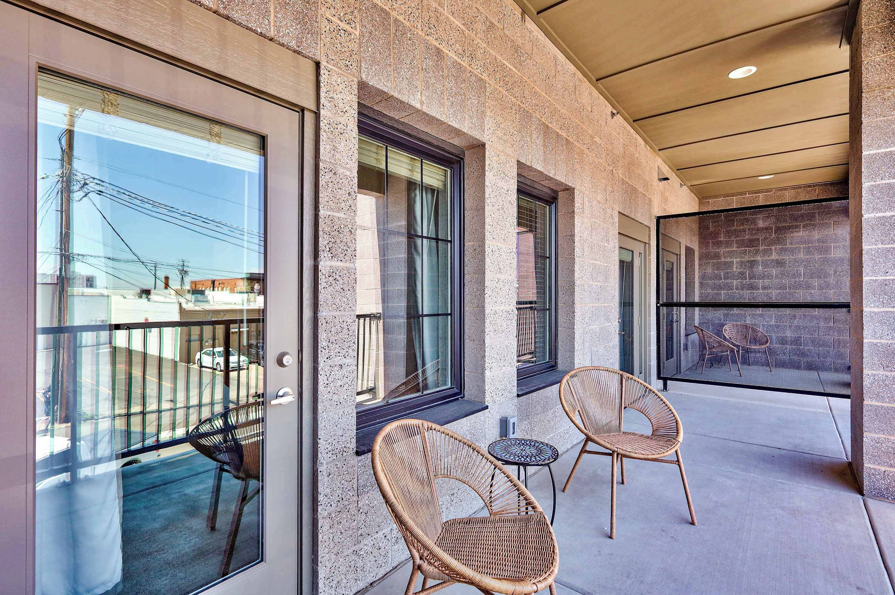 A modern building exterior with large windows, a balcony with wicker furniture, and a stone facade.