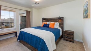 Un dormitorio con cama, mesita de noche y ventana con cortinas.