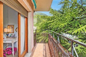 Ein Balkon mit Blick auf üppige, grüne Bäume und einen Berg im Hintergrund.