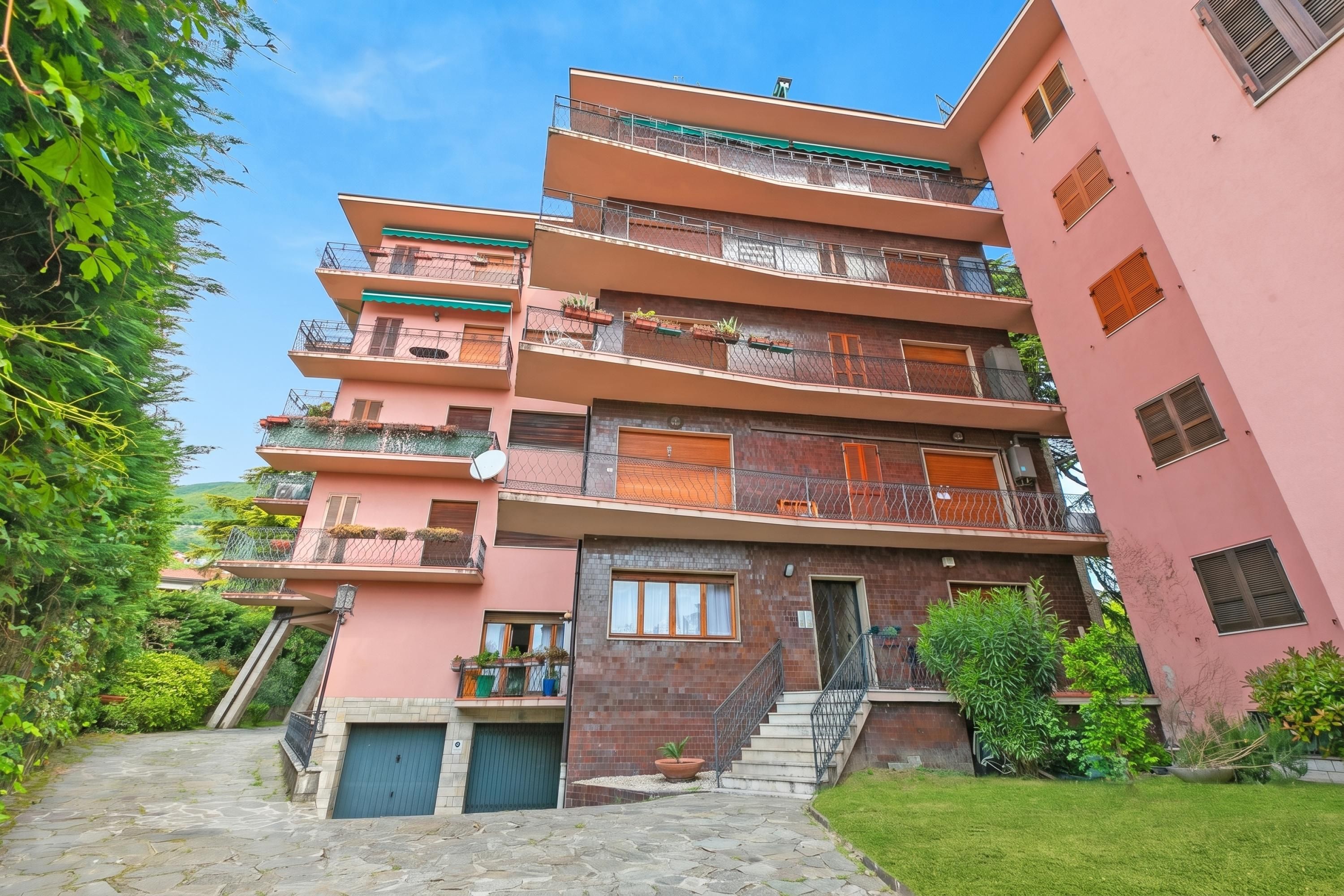A multi-story residential building with balconies, a staircase, and a garden area.