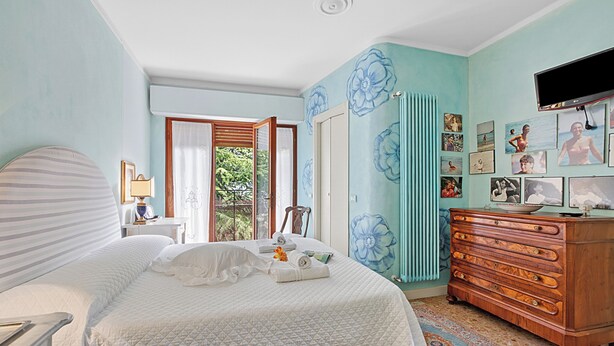 A bedroom with a bed, dresser, and wall art. - Roma 62 Lake View,terrace & Private Park (Toscolano Maderno)