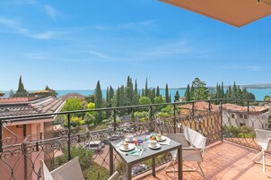 A terrace with a table set for dining, overlooking a scenic view of trees and a body of water.
