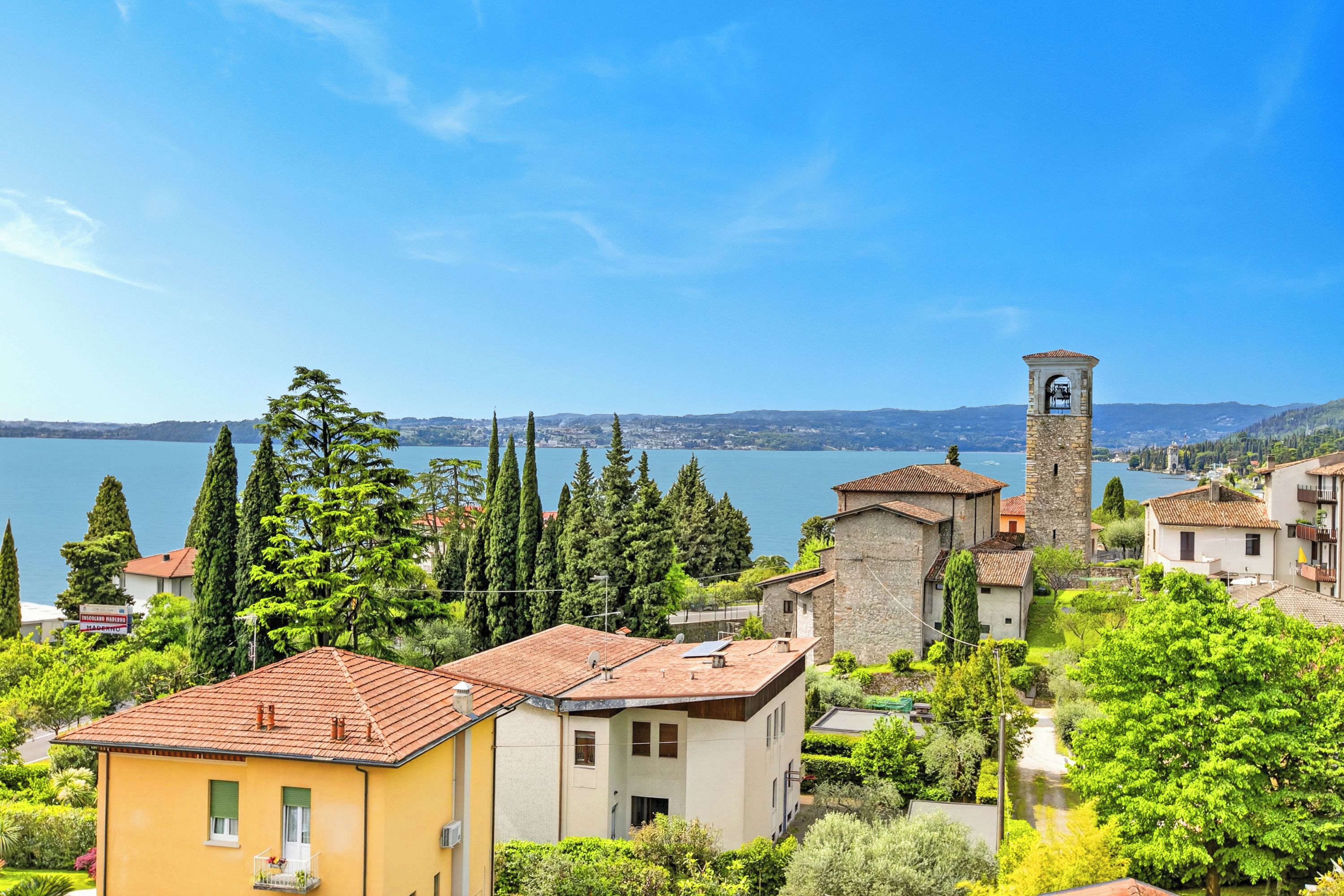 Un borgo costiero dall'architettura tradizionale, con una torre imponente e un lago sullo sfondo.
