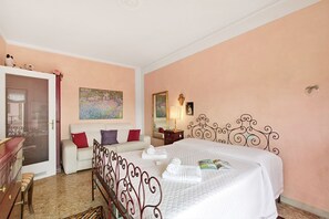 Ein Schlafzimmer mit einem Bett, einem weißen Schlafsofa, einer Kommode und einer Tür zu einem anderen Raum.