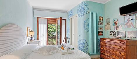 A bedroom with a bed, dresser, and wall art.