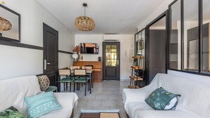 Una sala de estar moderna con un sofá, un comedor con mesa y sillas, y una cocina al fondo.