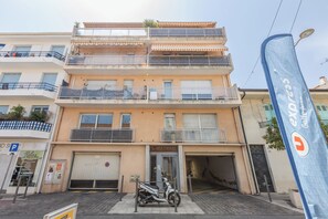 Un edifici de diverses plantes amb entrada a nivell del carrer, una moto visible i una bandera amb un logotip.