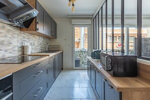 A modern kitchen with a built-in oven, a microwave, and a coffee machine. - Design 2BR | Private Parking, Beach & Train (Golfe Juan Vallauris)