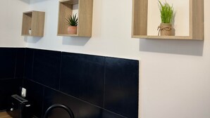 Una cocina moderna con azulejos negros, un lavamanos y estantes de madera con plantas.
